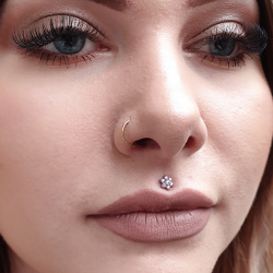 A tiny flower is worn in a healed medusa piercing. Jewellery from Anatometal