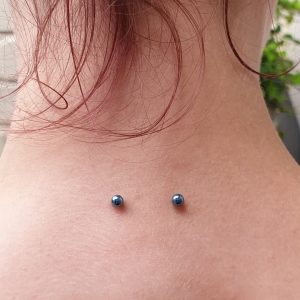 the nape of the neck pierced with a surface bar with blue balls