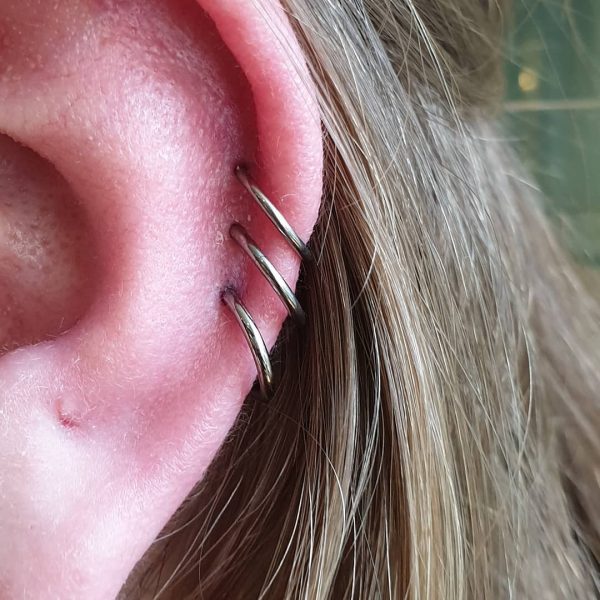 three healed helix piercings wearing segmented hinge rings hanging close together