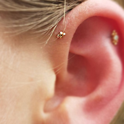 A quad of four gold bead s in a forward helix piercing and a blurred out piece in a helix