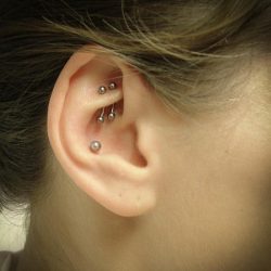 a double rook piercing wearing two side by side curved bars and a conch piercing with a plain ball