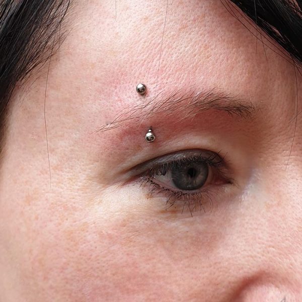 an eyebrow piercing with silver Anatometal balls