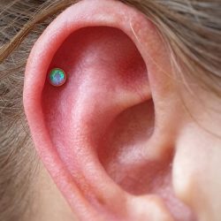 a helix piercing with a light blue opal