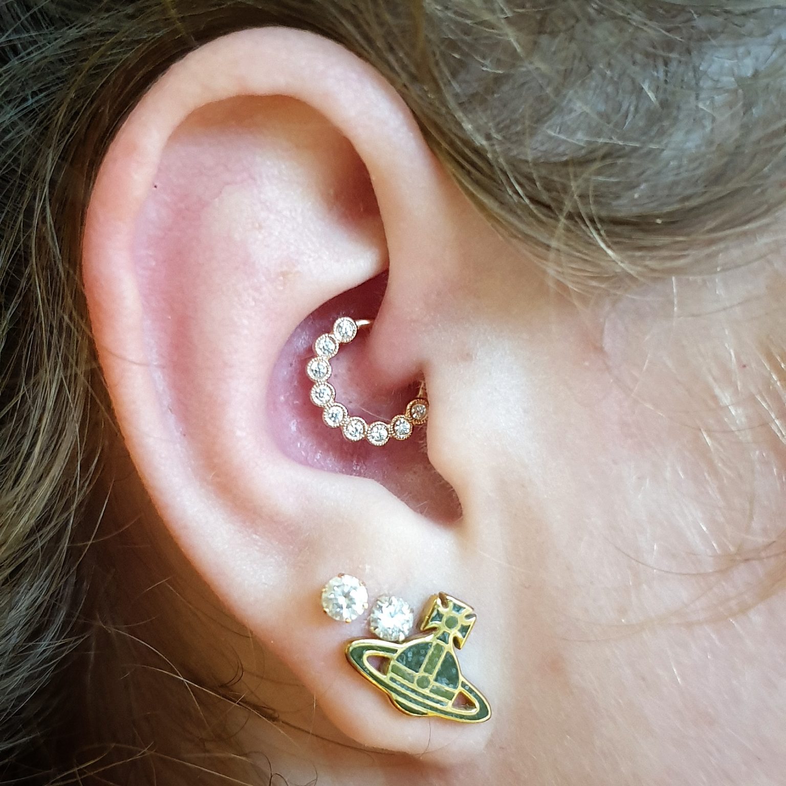 a Maria tash scalloped ring with clear CZ's in a daith piercing