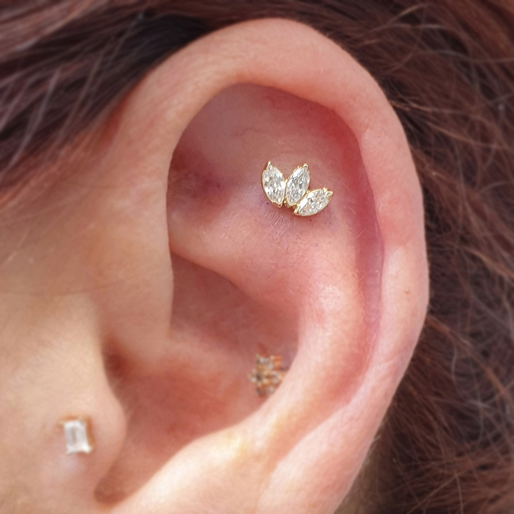The upper flat area of an ear thats been pierced with a three gem Marquise attachment from Anatometal
