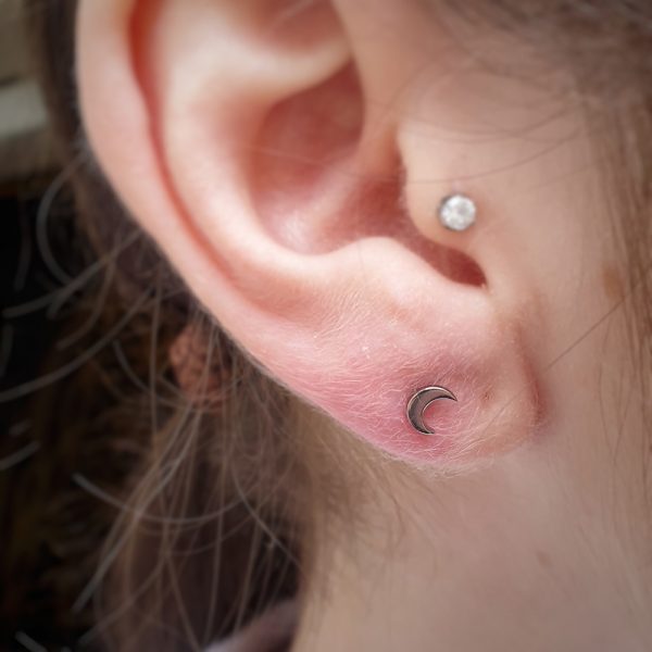 a titanium Anatometal moon end in a lobe piercing and a prong with CZ in a tragus