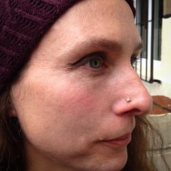 A lady in a red hat with her new nose piercing, wearing a Burst from Bodygems
