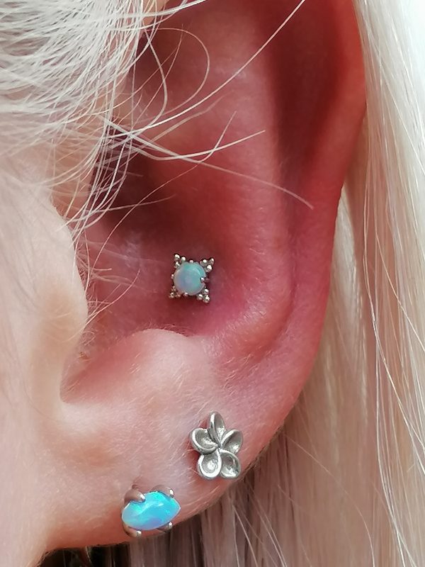 two clients own lobe pieces with a conch piercing wearing a white opal in a white gold zia end from Anatometal