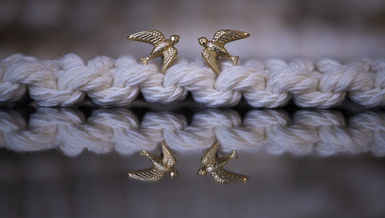 two gold birds balances on rope, showing the mirror reflection below. jewellery from BVCLA