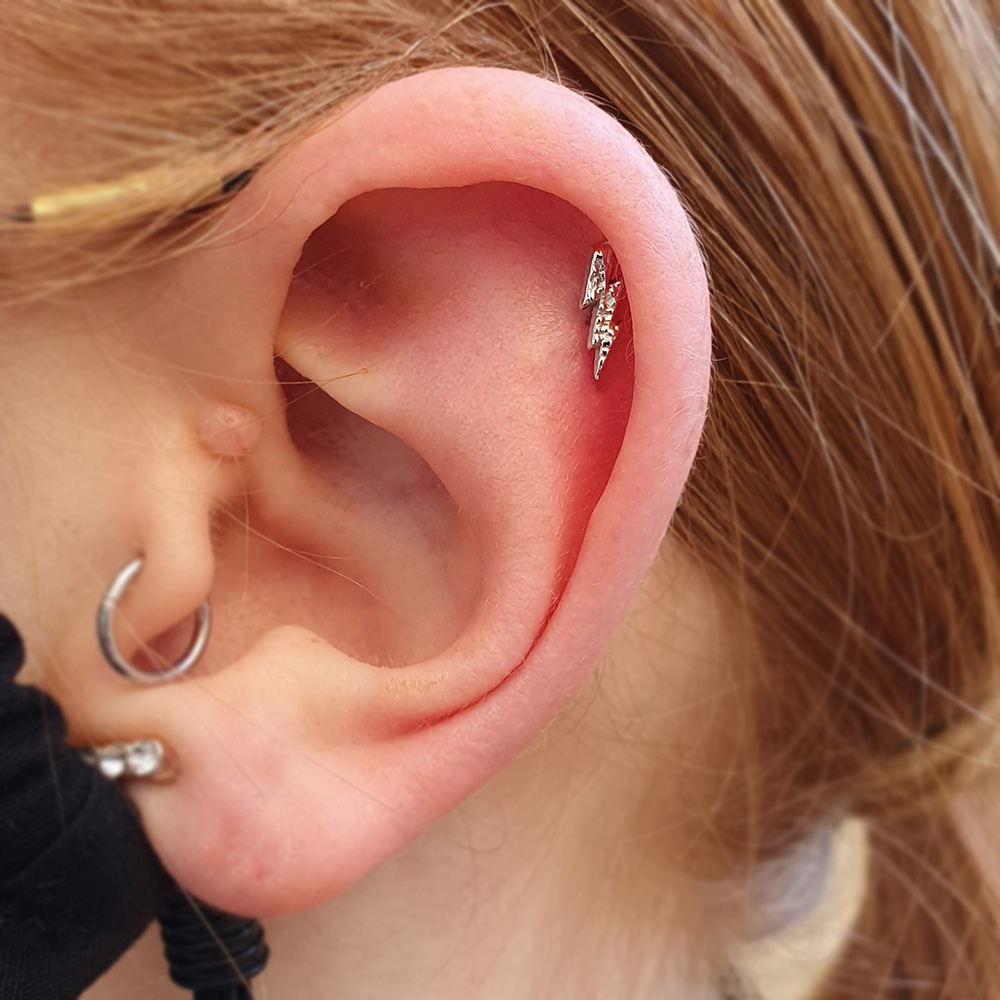 A hammered lightning bolt in a helix piercing from Bodygems as well as a ring in a tragus piercing